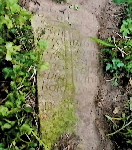 Nagrobek Józefa Reschitza o zwężającym się kształcie, z wyrytym krzyżem rozdzielającym inskrypcję. Otoczony trawą i częściowo pokryty mchem.