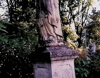 Grób oznaczony figurą Matki Boskiej Różańcowej na trójstopniowym cokole. Matka Boska w geście modlitewnym z różańcem na prawej ręce, ubrana w długą suknię, płaszcz i welon.