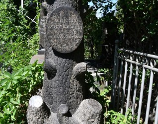Nagrobek Kajetana Baczkowskiego z podstawą stylizowaną na korzenie drzewa i cokołem jako pień drzewa. Z przodu owalna tabliczka z rytą inskrypcją. Otoczony zielenią i metalowym ogrodzeniem.