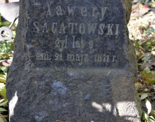 Nagrobek Ksawerego Sagatowskiego, kamienny blok z wyrytą inskrypcją. Krzyż niezachowany. Otoczony opadłymi liśćmi.