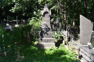 Grób Marii i Stanisława Krasnopolskich z wielopoziomową podstawą i inskrypcją z przodu, otoczony ogrodzeniem z łańcucha. Grób znajduje się na zalesionym cmentarzu.