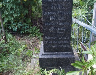Nagrobek Marii Szulc z wyrytym tekstem, otoczony zielenią. Kamień stoi na dwustopniowym cokole, pierwotnie zwieńczony krzyżem, obecnie brakującym.
