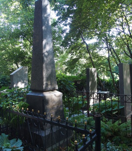 Nagrobek Emilii Ilnickiej oznaczony obeliskiem na dwustopniowym cokole z rytym napisem. Otoczony metalowym ogrodzeniem z dekoracyjnymi elementami. W tle drzewa i zieleń.