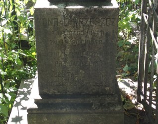 Nagrobek Konrada Wrzeszcza z inskrypcjami, pierwotnie oznaczony krzyżem. Dwustopniowy cokół o profilowanych i ściętych krawędziach, otoczony zielenią.