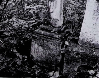 Nagrobek Katarzyny Rudik z krzyżem na cokole. Krzyż ma ścięte krawędzie i wypukłorzeźbioną postać Chrystusa na przecięciu ramion. Inskrypcja wyryta w ramie łuku mauretańskiego.