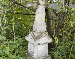 Nagrobek Macieja Szwaluka z fazowanym krzyżem na cokole w zalesionym terenie. Cokół przypomina kapliczkę z dwuspadowym daszkiem i płyciną inskrypcyjną o prostokątnie ściętych narożach.