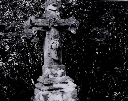 Nagrobek z krzyżem na cokole, z ramionami zakończonymi trójliściem i reliefem Chrystusa na przecięciu. Powyżej titulus. Cokół lekko zwęża się ku górze z profilowanymi krawędziami.