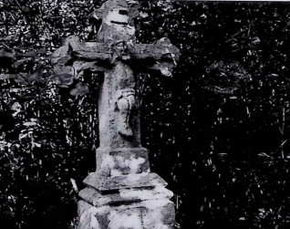 Nagrobek z krzyżem na cokole, z ramionami zakończonymi trójliściem i reliefem Chrystusa na przecięciu. Powyżej titulus. Cokół lekko zwęża się ku górze z profilowanymi krawędziami.