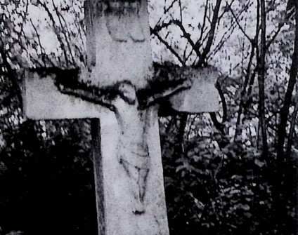 Nagrobek z krzyżem na cokole i dwustopniowej podstawie. Krzyż szerszy u dołu z reliefem Chrystusa na przecięciu ramion. Powyżej titulus. Cokół ma ścięte górne krawędzie.