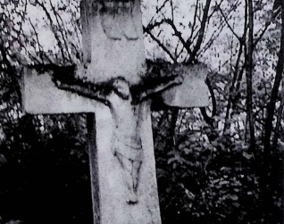 Nagrobek z krzyżem na cokole i dwustopniowej podstawie. Krzyż szerszy u dołu z reliefem Chrystusa na przecięciu ramion. Powyżej titulus. Cokół ma ścięte górne krawędzie.