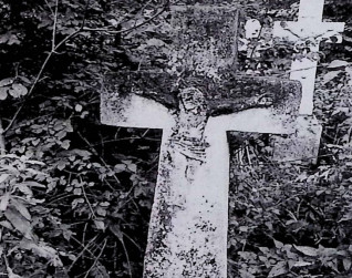 Nagrobek z krzyżem na cokole, szerszy u dołu. Na przecięciu ramion wypukłorzeźba Chrystusa. Cokół lekko zwęża się ku górze, z przodu inskrypcja.