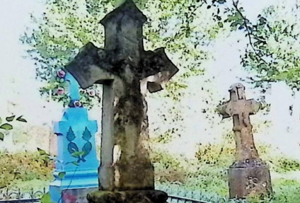 Grób oznaczony krzyżem z łukowym wykrojem, z reliefem Chrystusa na przecięciu ramion. Cokół zwęża się ku górze, z inskrypcją z przodu.