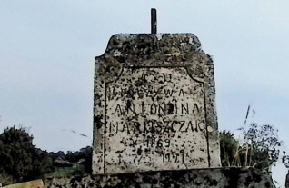 Nagrobek Antoniny Maruszczak z krzyżem na cokole. Górna część krzyża z płaskorzeźbionym titulusem. Cokół z daszkiem mansardowym i inskrypcją w ramie o ćwierćkolistych narożach.