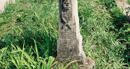 Mogiła z krzyżem na cokole z płaskorzeźbą Chrystusa Ukrzyżowanego, titulusem i czaszką ze skrzyżowanymi piszczelami. Poniżej inskrypcja ryta.