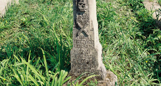 Mogiła z krzyżem na cokole z płaskorzeźbą Chrystusa Ukrzyżowanego, titulusem i czaszką ze skrzyżowanymi piszczelami. Poniżej inskrypcja ryta.