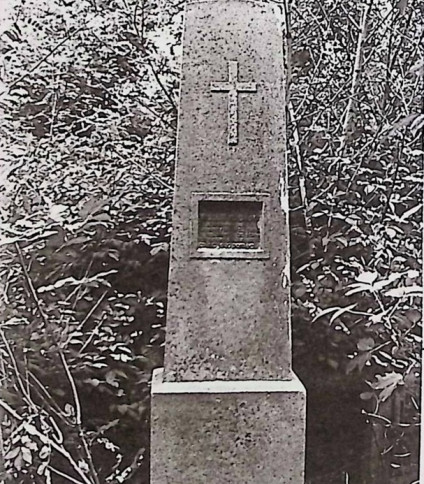 Nagrobek Tadeusza Kościńskiego z obeliskiem z płaskorzeźbionym krzyżem i metalową tablicą w prostokątnej niszy, otoczony żeliwnym ogrodzeniem z piaskowcowymi słupkami.