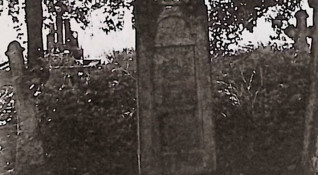 Grób oznaczony krzyżem na cokole z wieńcem kwiatowym. Cokół ma trzy płyciny, z inskrypcją z przodu. Lewa strona pokazuje ślady po usuniętej tablicy inskrypcyjnej.