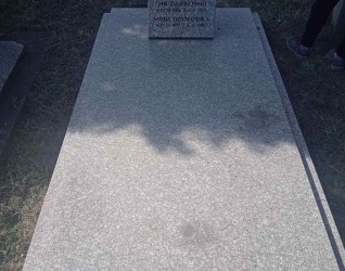 Nagrobek Jana i Marii Dziewońskich z tablicą inskrypcyjną z wyrytym liściem i czarnymi literami. Tablica pochylona do tyłu, wsparta na podpórce. Gzyms nagrobka szerszy od pozostałych elementów.