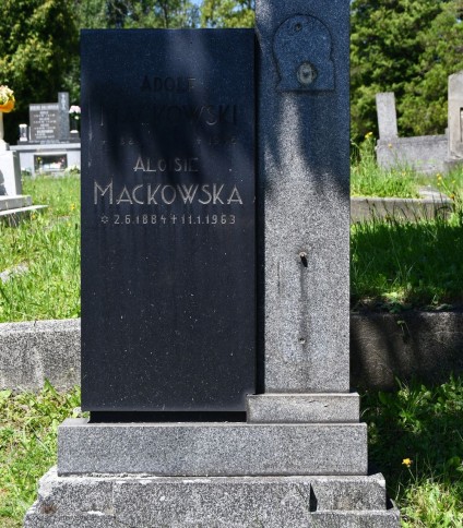 Modernistyczna stela oznaczająca grób rodziny Mackowskich. Składa się z kubicznych brył z szeroką podstawą, cokołem i tablicą z inskrypcją. Pionowy słupek z widocznym śladem po mocowaniu krzyża.