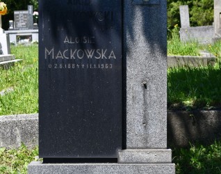 Modernistyczna stela oznaczająca grób rodziny Mackowskich. Składa się z kubicznych brył z szeroką podstawą, cokołem i tablicą z inskrypcją. Pionowy słupek z widocznym śladem po mocowaniu krzyża.