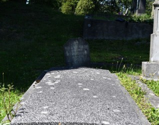 Nagrobek rodziny Hansel z tabliczką z piaskowca z inskrypcjami z obu stron, przymocowaną do dwustopniowej płyty nagrobnej z betonu i lastryko za pomocą żelaznych prętów.