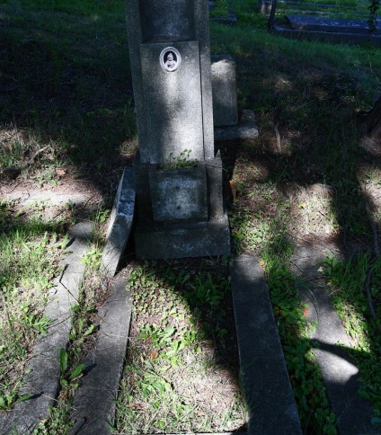 Grób Henryki Warynicowej z kapliczkowym zwieńczeniem i opaską. Pozioma podstawa i cokół z wgłębieniem pełnią funkcję doniczki. Półkolista nisza zawiera tablicę z inskrypcją i zdjęciem.