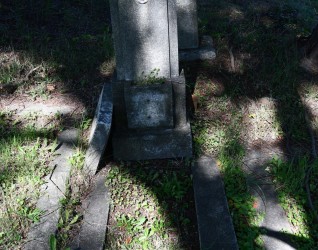 Grób Henryki Warynicowej z kapliczkowym zwieńczeniem i opaską. Pozioma podstawa i cokół z wgłębieniem pełnią funkcję doniczki. Półkolista nisza zawiera tablicę z inskrypcją i zdjęciem.