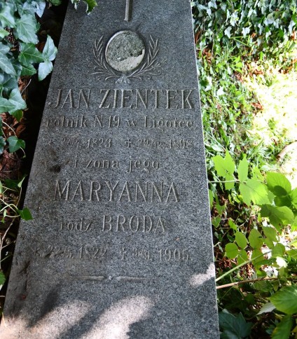 Nagrobek Jana Zientka i Marianny Brody z wyrytymi inskrypcjami i krzyżem. Kamień otoczony bluszczem i trawą.