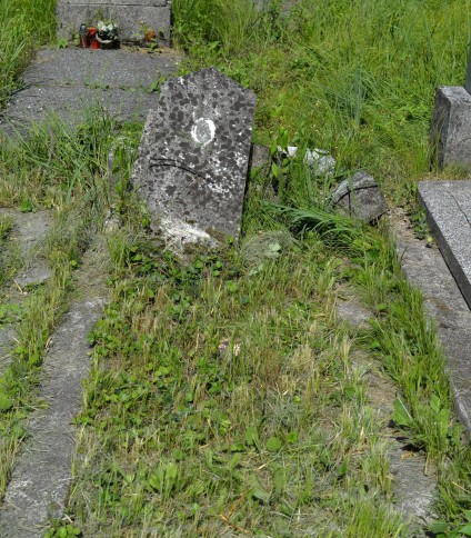Grób oznaczony obeliskiem na prostokątnej betonowej podstawie, otoczony trawą. Obelisk zwieńczony trapezem. Inskrypcje nieczytelne.