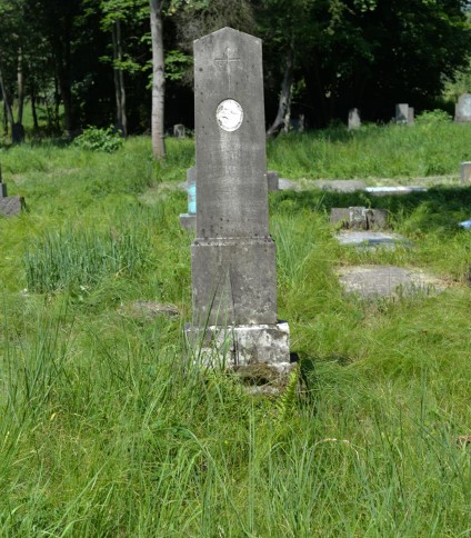 Grób oznaczony dwustopniowym marmurowym obeliskiem z dekoracyjnym krzyżem i inskrypcją. Cokół przypomina stos kamieni. Miejsce otoczone trawą.