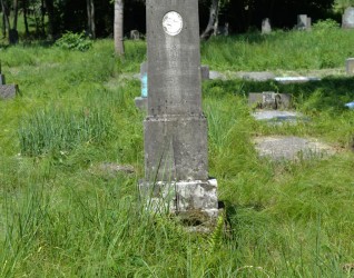 Grób oznaczony dwustopniowym marmurowym obeliskiem z dekoracyjnym krzyżem i inskrypcją. Cokół przypomina stos kamieni. Miejsce otoczone trawą.