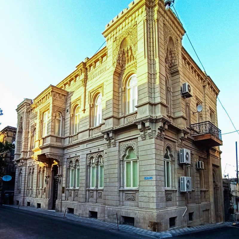 Dom Aga-Bały Gulijewa w Baku, Eugeniusz Skibiński, 1899, 2-kondygnacyjny budynek na planie prostokąta, murowany z cegły, tynkowany z boniowaniem; elementy dekoracyjne żeliwne