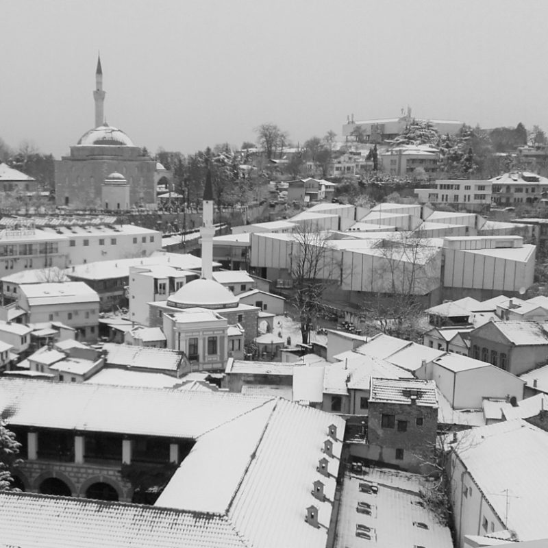 A bird’s-eye view of snow-covered Skopje, taken from the Museum of Contemporary Art on Kale Hill. The museum’s white, windowless structure contrasts with the surrounding Ottoman architecture.