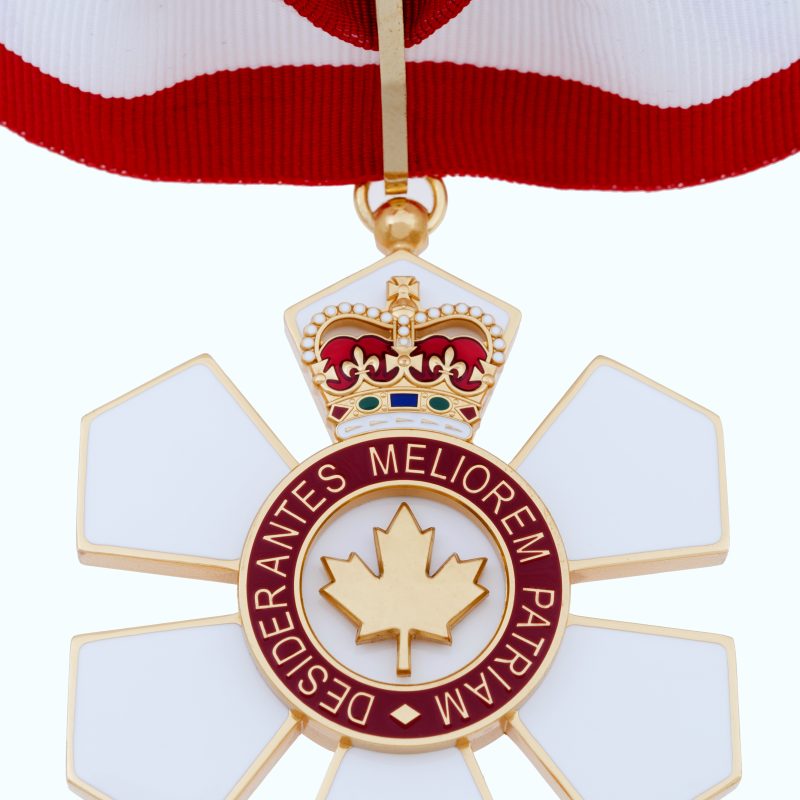 A Medal of the Order of Canada with a red and white ribbon, featuring a golden maple leaf in the centre and the inscription 'Desiderantes Meliorem Patriam'.