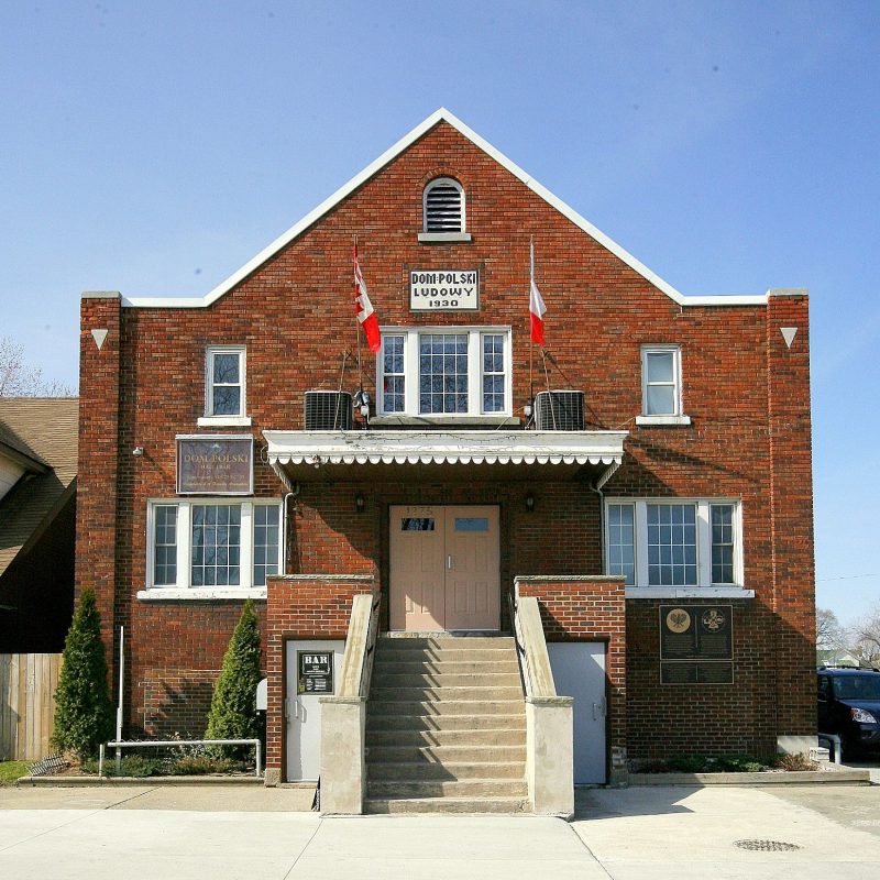 The building of the Polish People’s House in Windsor, Canada, with a brick façade, two flags (the Canadian and Polish flags) at the front, and the inscription ‘Polish People’s House 1930’.