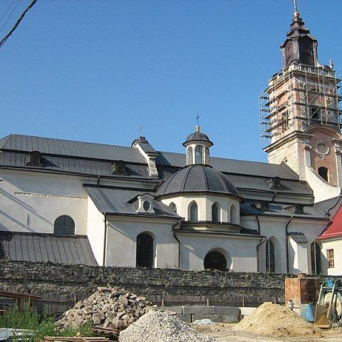 Église Saint-Nicolas à Kamianets-Podilskyi, bâtiment baroque avec une tour en rénovation, entouré de matériaux de construction.