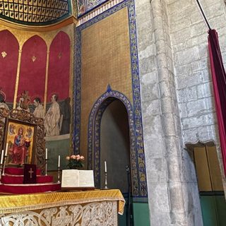 Intérieur de la cathédrale arménienne de Lviv montrant l'autel avec des sculptures complexes, des peintures religieuses et une arche décorée. Les murs présentent des éléments polychromes et dorés.