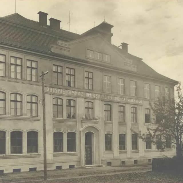 Photographie historique du Gymnase Réel Polonais nommé d'après Juliusz Słowacki à Orłowa. Le bâtiment a une façade symétrique avec des fenêtres cintrées et une entrée centrale. Des arbres sont visibles à droite.