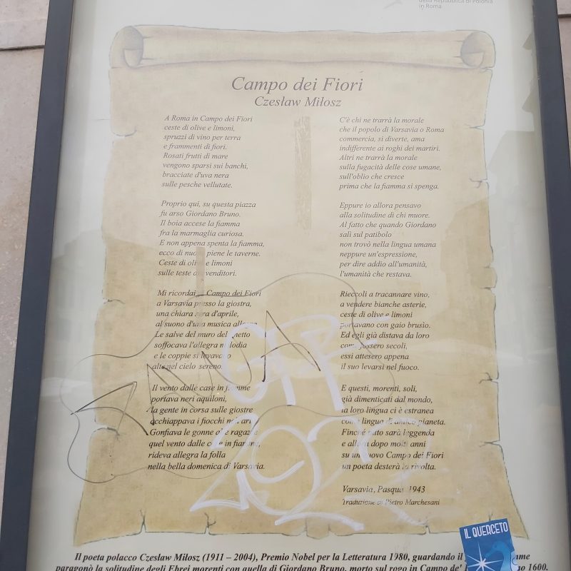 Tablica z wierszem 'Campo dei Fiori' Czesława Miłosza w języku polskim i włoskim, umieszczona na placu Campo dei Fiori w Rzymie. Tablica jest oprawiona i pokryta graffiti.