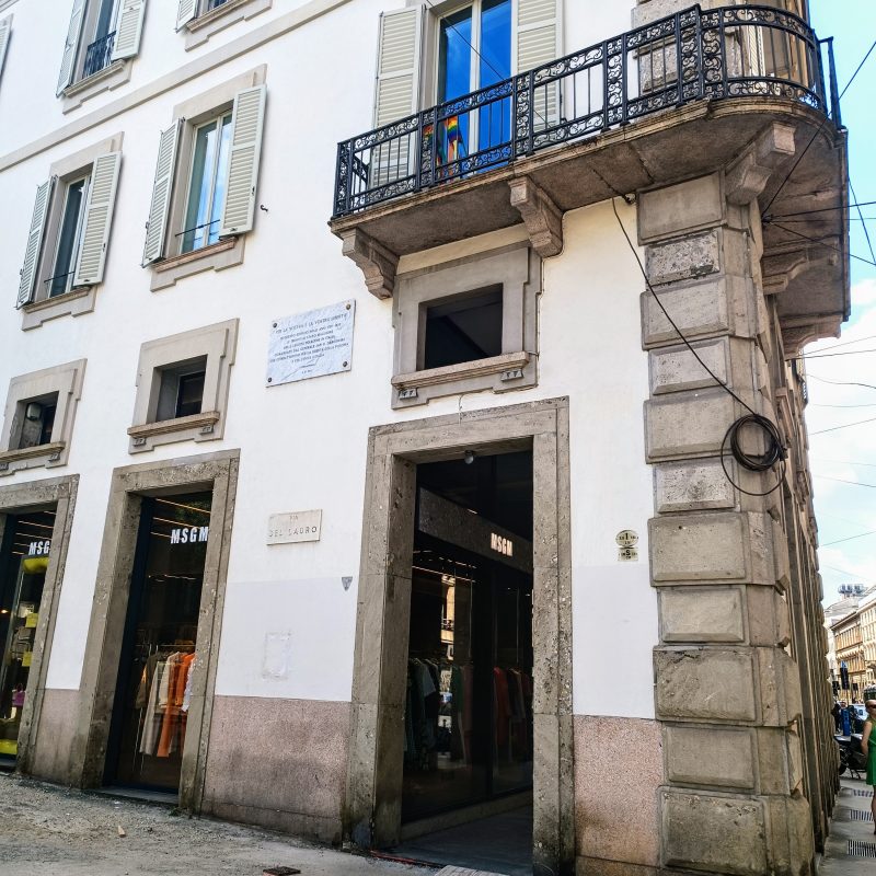 Plaque commemorating Adam Mickiewicz's stay in Milan on the facade of Casa Trotti at Piazzetta Bosi. The building features multiple windows with shutters and a decorative balcony.