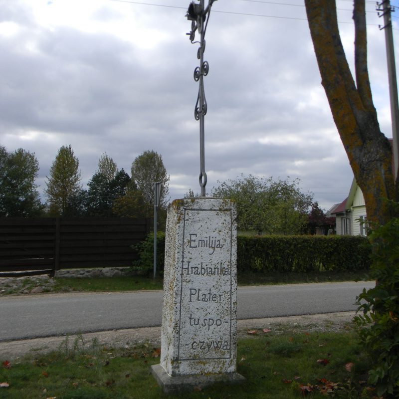Obelisk Emilii Plater w Kopciowie z inskrypcją: 'Emilija Hrabianka Plater tu spoczywa / Zeszła w Bogu d. 23. Grud. 1831. Roku'. Otoczony trawą, w tle drzewo i droga.