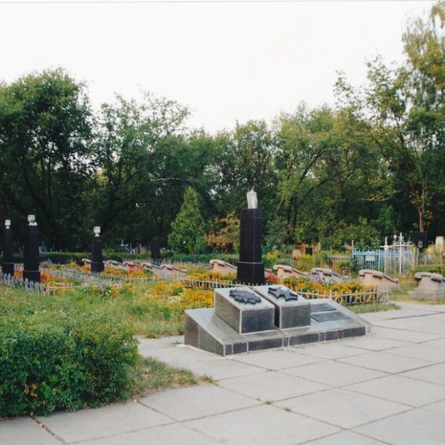 Tombes de soldats polonais de 1944 au cimetière de Kyiv-Darnytsia. Obélisques en marbre noir avec vases blancs, entourés de clôtures métalliques basses. Deux plaques horizontales avec des aigles polonais et les noms des soldats tombés.