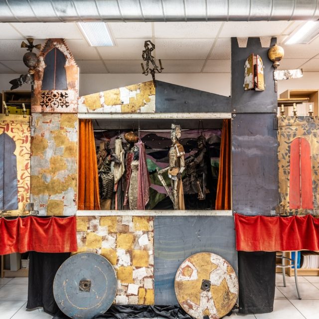 Wagon théâtral avec marionnettes de Jacek Stryjeński, représentant des chevaliers et des cavaliers orientaux, exposé à la Fondation Helveto-Polonicum à Fribourg. Le wagon est orné d'éléments métalliques et en tissu.