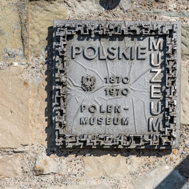 Plaque en pierre commémorant le 100e anniversaire du Musée polonais à Rapperswil, avec une bordure géométrique et l'emblème de l'aigle polonais. Inscription : 'Polskie Muzeum / Polen Museum 1870 / 1970'.