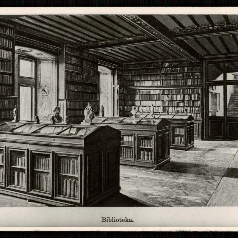 Intérieur de la Bibliothèque du Musée National Polonais à Rapperswil, avec des étagères remplies de livres et des vitrines avec des bustes. La pièce a un plafond en bois et de grandes fenêtres.