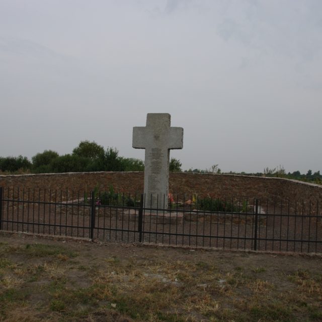 Pomnik w formie granitowego krzyża z polskim orłem i napisami po polsku i ukraińsku, otoczony kamiennym murkiem i metalowym ogrodzeniem, upamiętniający Polaków zamordowanych w Lidawce w 1943 roku.