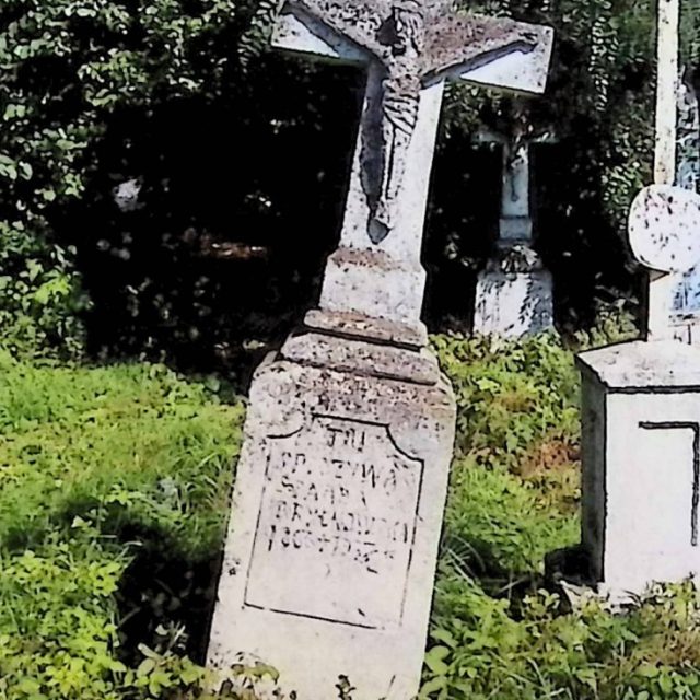 Nagrobek Anny Bryłkowskiej z krzyżem na cokole i dwustopniowej podstawie. Krzyż z rzeźbioną postacią Chrystusa i inskrypcją poniżej. Cokół ma profilowane krawędzie i wyrytą ramę z zaokrąglonymi narożnikami.