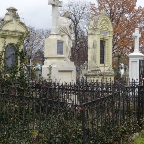 L'ancien cimetière arménien de Kuty, avec ses pierres tombales ornées et sa clôture en fer, entouré d'arbres aux couleurs de l'automne.