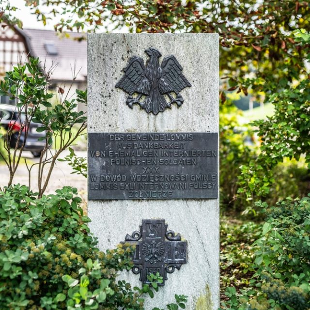 Monument en pierre à Lommis avec un aigle et une croix en bronze, entouré de verdure. Inscription en allemand et polonais exprimant la gratitude des anciens soldats polonais internés.