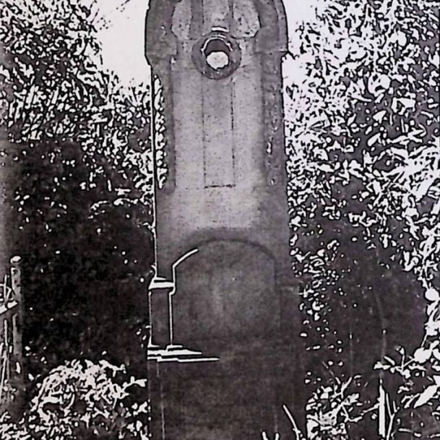 Gravestone of Franciszek Kondyjowski with a stele on a three-tiered pedestal. The stele features a laurel garland and a cross relief. A ceramic medallion fragment is visible at the cross intersection.